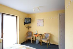 a room with a table and two chairs and a tv at Landgasthaus Pension Schmidthöfer in Berschweiler