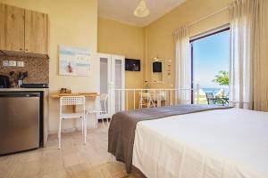 a bedroom with a bed and a kitchen with a table at Thalassa Apartments & Studios in Kavos