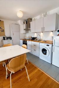 a kitchen with white appliances and a table and chairs at Le Clos Savignac in Trouville-sur-Mer