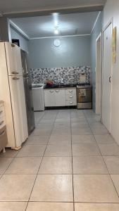 a large kitchen with white appliances and a large floor at Quarto 1 econômico Centro Itajaí in Itajaí +4 photos