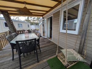 a porch with a swing and a table and chairs at Bungalow mahi-mahi in Lacanau +27 photos