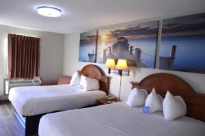 a hotel room with two beds and a painting on the wall at Days Inn by Wyndham Trumann AR in Trumann +29 photos