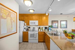 a kitchen with wooden cabinets and white appliances at Kaanapali Shores 512 in Kaanapali +33 photos