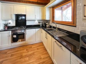 a kitchen with white cabinets and black counter tops at Avocet Lodge in Horncastle