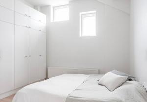 a white bedroom with a bed and two windows at Modern Two-Bedroom Apartment with Sauna & Free Parking in Turku