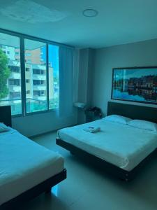 a bedroom with two beds and a large window at Hotel Suites Caribe in Barranquilla