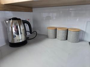 a tea kettle on a counter next to a stack of plates at Pine Ridge B6 in Reighton