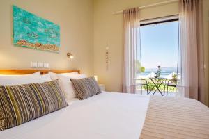 a bedroom with a white bed and a large window at Thalassa Apartments & Studios in Kavos