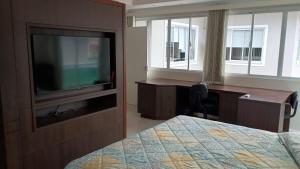 a bedroom with a bed and a desk and a television at Private Suite Confortable Stay in Florianópolis