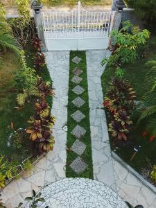 a garden with a stone pathway with plants and a white fence at La plus grande source d'eaux chaudes F1 in Bouillante