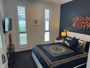 a bedroom with a bed and two windows at The Waterways Boathouse in Whitianga