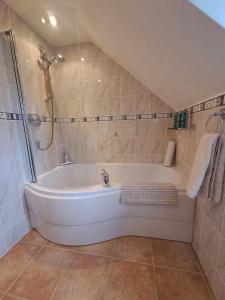 a white bath tub in a bathroom with a shower at Hollybank, Kyleakin in Kyleakin