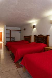 zwei Betten in einem Zimmer mit roter Bettwäsche in der Unterkunft Hotel Morada de Paz in Colorines