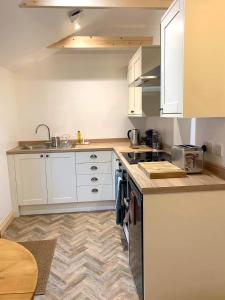 a kitchen with white cabinets and a sink at Mini Treacle Cottage in Dundry