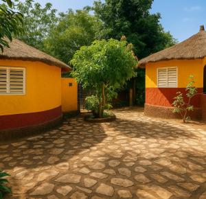 a house and a tree in front of a driveway at Ecogîte Dégg-Jàmm in Mbour