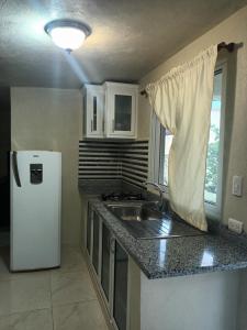 a small kitchen with a sink and a refrigerator at Casa taina in Jarabacoa