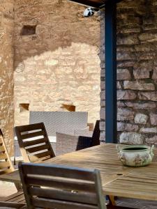 a wooden table with chairs and a stone wall at La Gemma del Subasio nel Castello di Collepino - Spello in Collepino