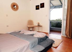 a bedroom with a bed with a chair and a balcony at AnastasiaSunsetView in Souda