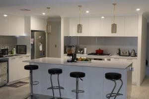 a kitchen with white cabinets and a island with bar stools at Piara Sojourn in Perth