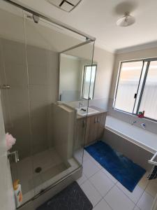 a bathroom with a shower and a tub and a sink at Piara Sojourn in Perth