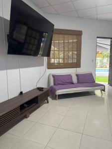 a room with a bed with purple pillows and a tv at Casa Yasmin in San Mateo