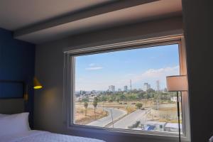 a bedroom with a window with a view of a city at Tru By Hilton Puebla Angelopolis in Puebla +20 photos