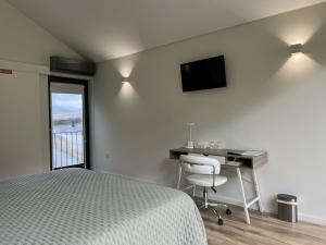 a bedroom with a bed and a desk and a television at Ermida Vista Douro in Baião +28 photos