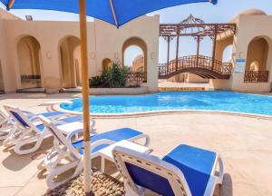 a swimming pool with chairs and an umbrella at OrientalCoast in Quseir