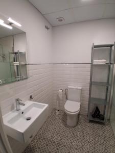 a bathroom with a white toilet and a sink at San Atón apartamentos in Badajoz +11 photos