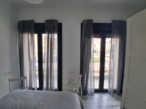 a bedroom with a bed and two large windows at San Atón apartamentos in Badajoz