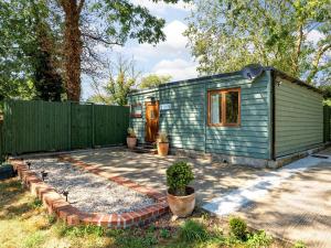 ein grünes Minihaus in einem Garten mit Zaun in der Unterkunft Island Lodge - Uk46767 in Little Baddow + 12 Fotos