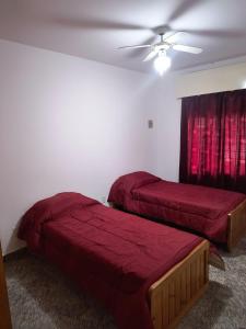 a bedroom with two beds and a ceiling fan at Alojamiento casa amueblada in Villa María