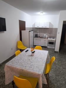 a dining room table with yellow chairs and a kitchen at Alojamiento casa amueblada in Villa María