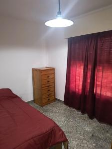 a bedroom with a bed and a dresser and a red curtain at Alojamiento casa amueblada in Villa María