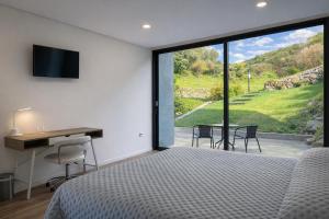a bedroom with a bed and a desk and a window at Ermida Vista Douro in Baião
