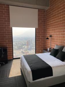 a bedroom with a large bed with a large window at Hotel Ecovergel Santa Lucia in Monterrey
