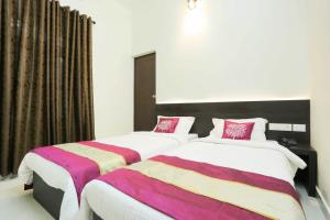 2 łóżka w pokoju hotelowym z różową i fioletową pościelą w obiekcie Hotel Prathiba Heritage w mieście Thiruvananthapuram