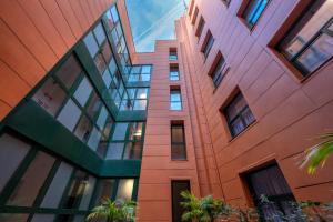 a tall orange building with windows and palm trees at Hotel SERHS Del Port in Barcelona
