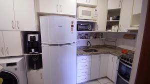 a white refrigerator in a kitchen with white cabinets at Apartamento Centro São Carlos in São Carlos +16 photos