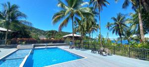 a resort swimming pool with palm trees in the background at Playa de Oro Lodge in Bahía Solano