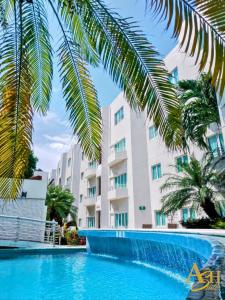 a swimming pool in front of a building with palm trees at Angeles Suites & Hotel in Veracruz