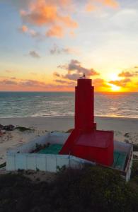 a red lighthouse on the beach at sunset at Casa Jo Fortim in Fortim +8 photos