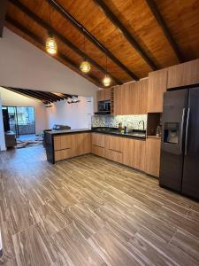a large kitchen with wooden cabinets and a refrigerator at Nido de Montaña Cabañas in Bello