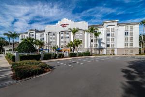 a large white building with palm trees in front of it at Hampton Inn Lake Buena Vista / Orlando in Orlando