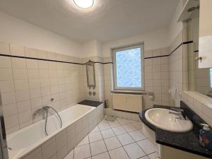 a bathroom with a bath tub and a sink at Home4You Hamburg-Neugraben EG in Hamburg