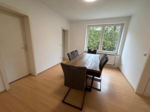 a dining room table with chairs and a large window at Home4You Hamburg-Neugraben EG in Hamburg +16 photos
