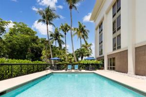 a swimming pool in front of a building with palm trees at Hampton Inn Naples-Central in Naples +53 photos