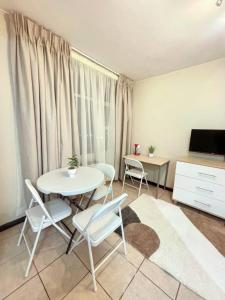 a living room with a table and chairs and a television at Durban Oceanic Apartment 117 in Durban