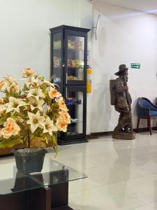 a vase of flowers and a statue in a room at HOTEL IBYZA Ipiales in Ipiales