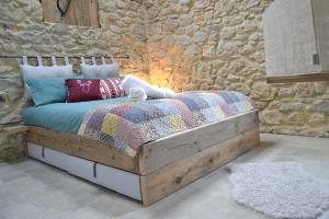 a bed in a room with a stone wall at Al Foér Guesthouse in Averara +40 photos